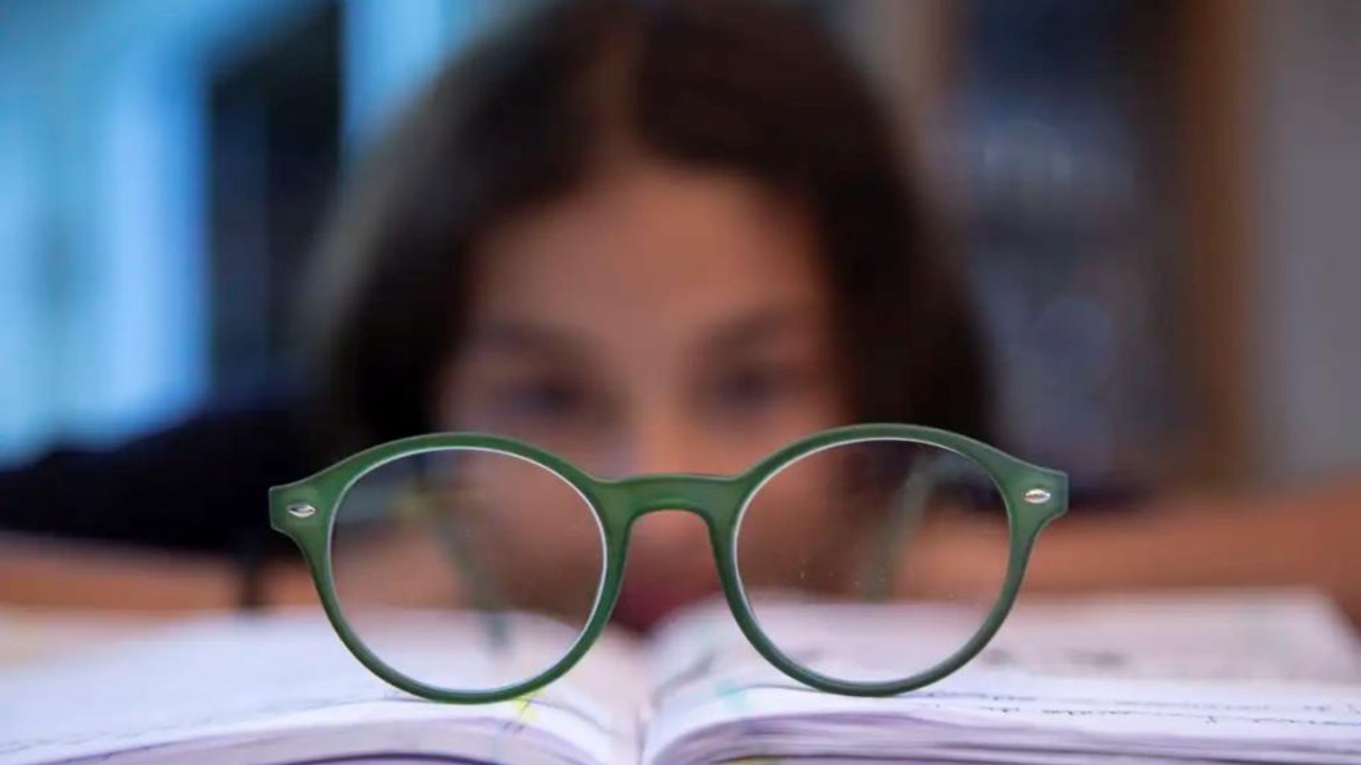 criança atrás de óculos em cima de livro